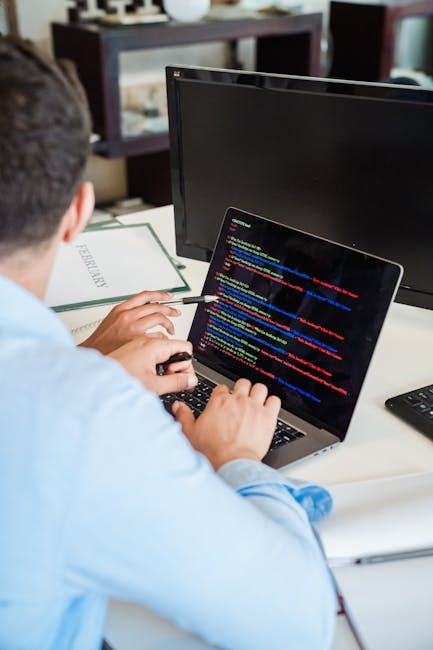 A laptop open on a desk displaying a coding environment with HTML and CSS code on the left side and a large calculator graphic on the right side. The screen shows various lines of code in a text edito